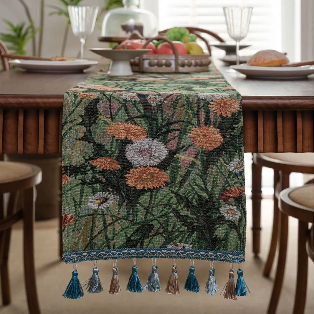 Beige jacquard table runner with floral pattern and long tassels laid on a wooden table.