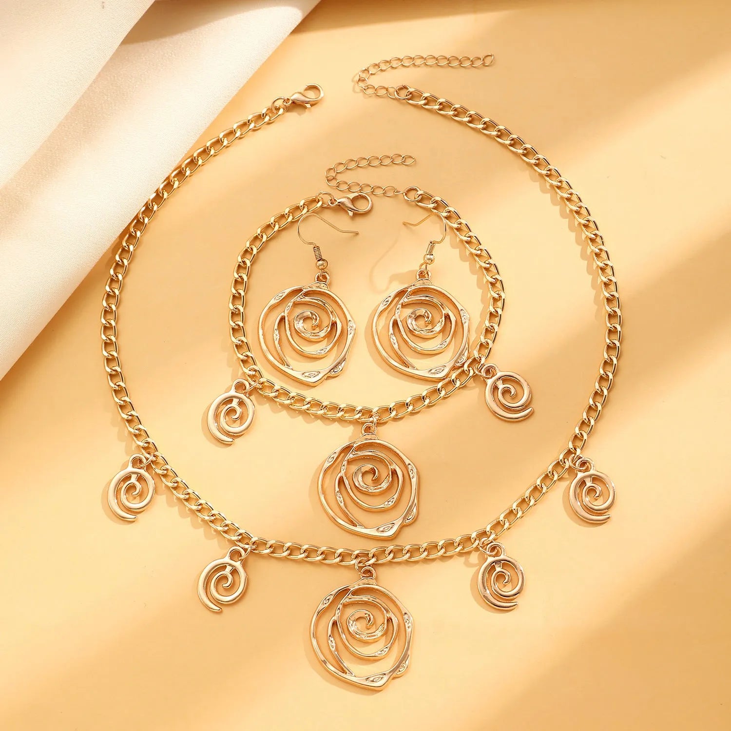 Gold or silver electroplated alloy jewellery set with spiral donut geometric shapes including necklace bracelet and ear hooks