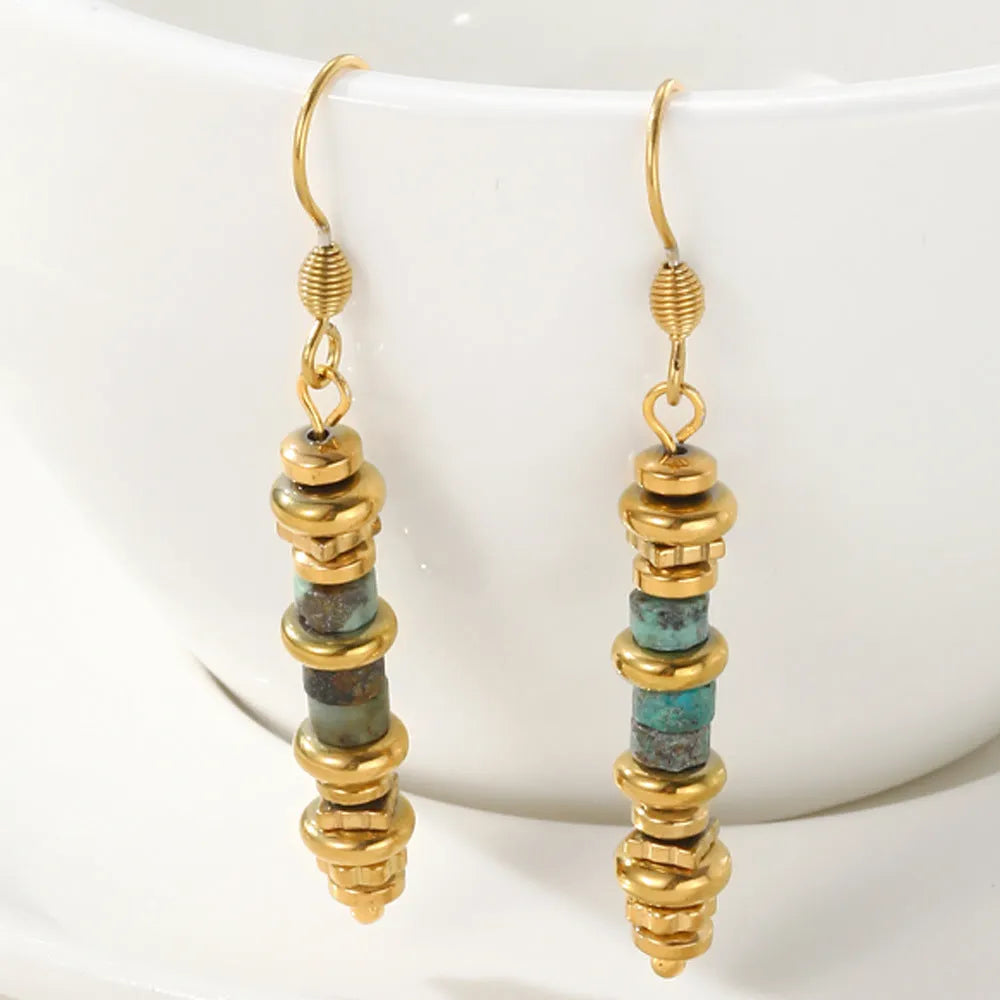 A pair of geometric-shaped, gold-toned dangle earrings on a plain background.