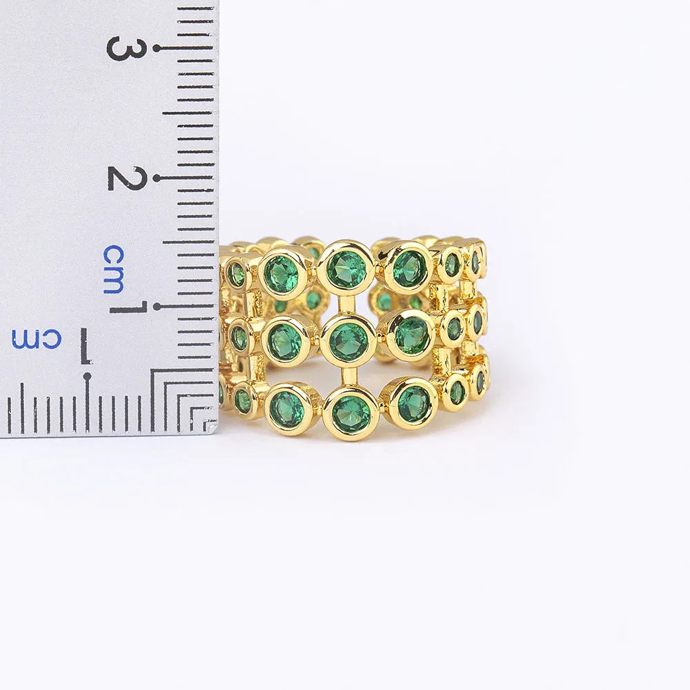 Copper ring with gold plating showing a wide, layered band fully set with green zircon stones.