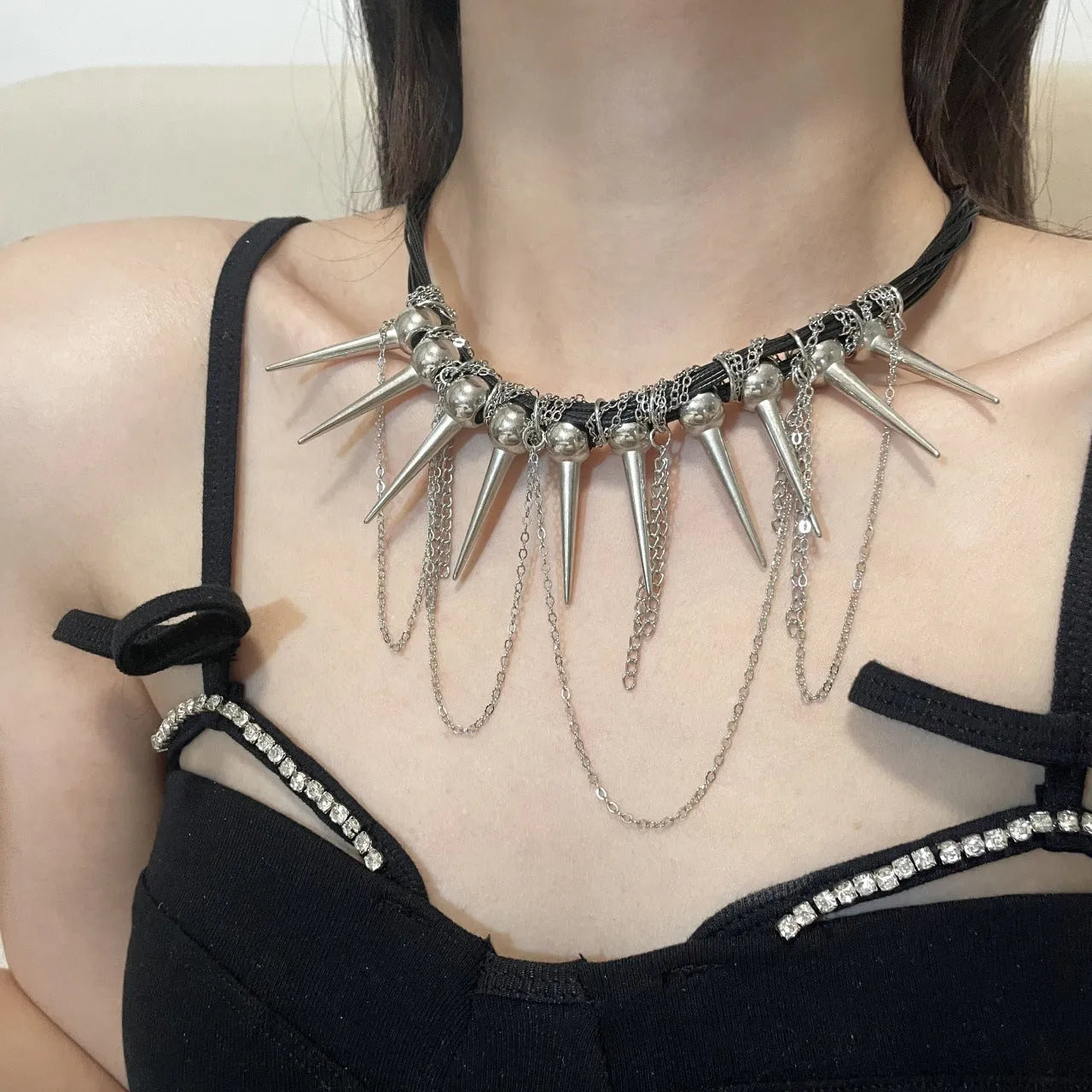 Leather necklace with round beads, a winding tassel, and silver point rivets on a white background.