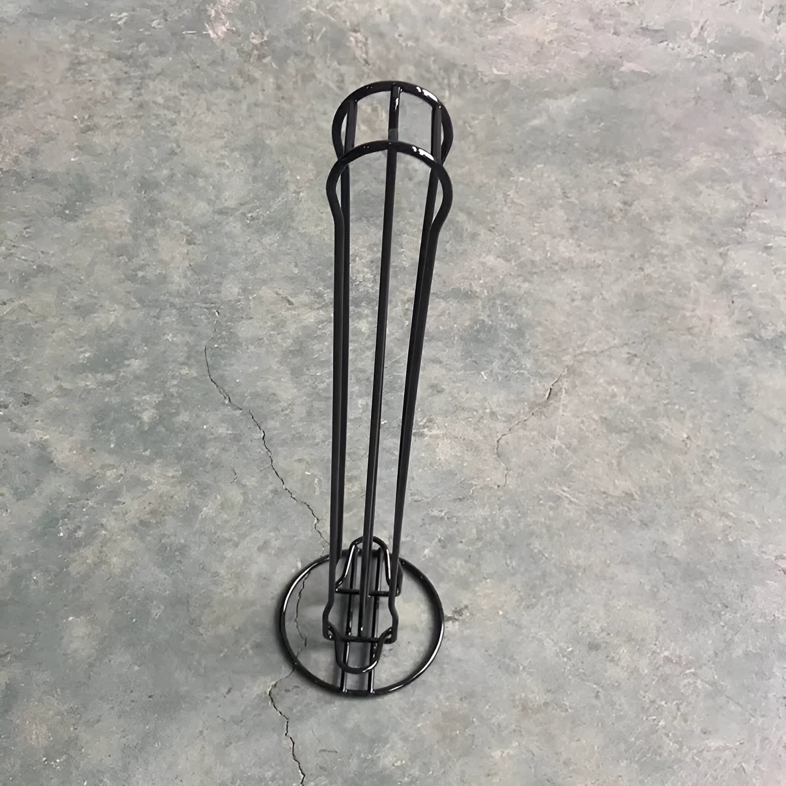 Black wrought iron coffee capsule storage rack holding pods on display shelves.