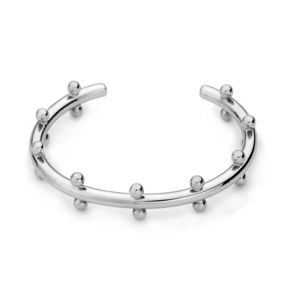Close-up of textured stainless steel C-shaped bean bead charm in gold finish, shown next to an alloy bracelet.