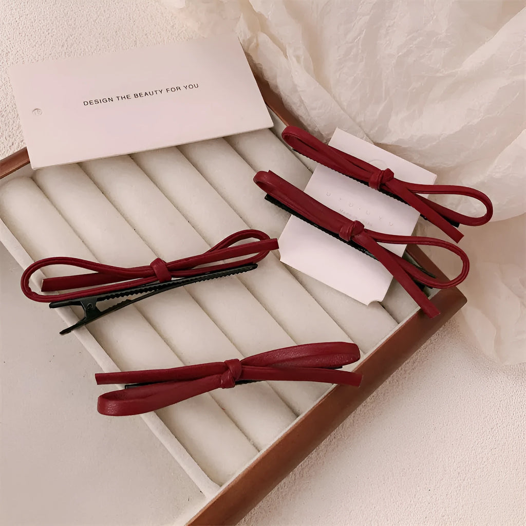 Wine red leather bow hair barrettes shown from multiple angles on dark background