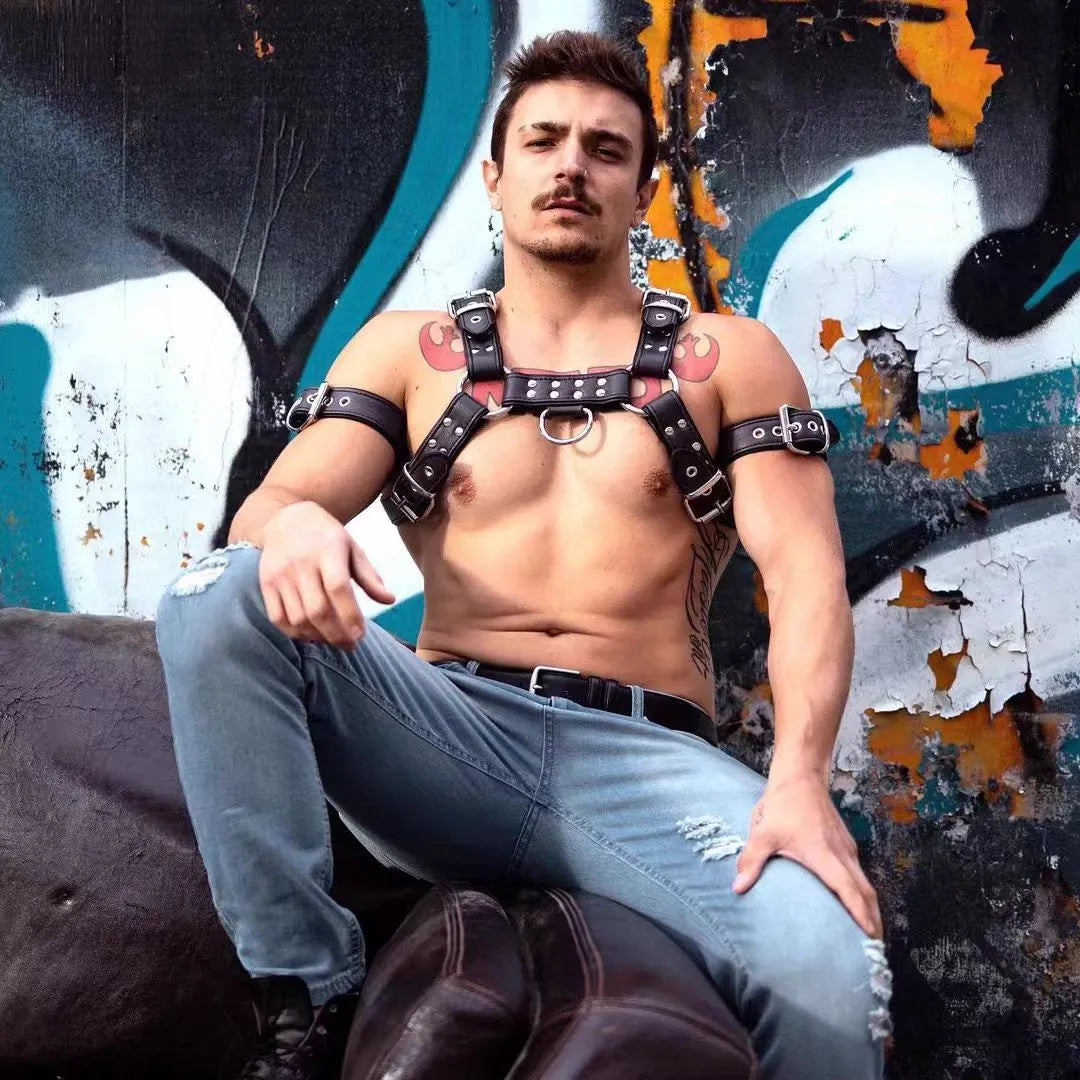 Black leather chest strap with metal buckle and rivet detailing for adult male costume wear