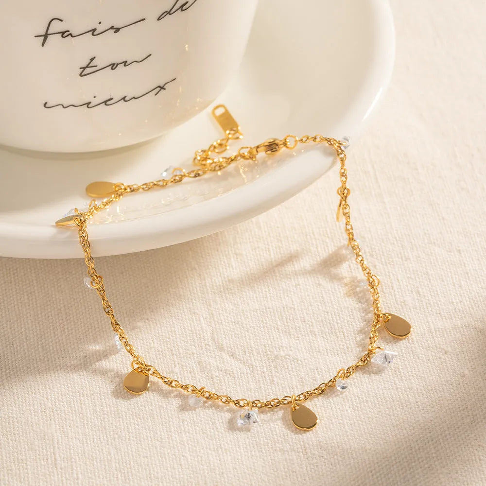 Close-up of a women's stainless steel anklet with a water drop pendant and tassel detail.