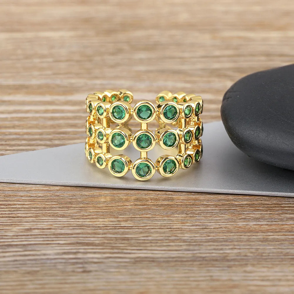 Copper ring with gold plating showing a wide, layered band fully set with green zircon stones.