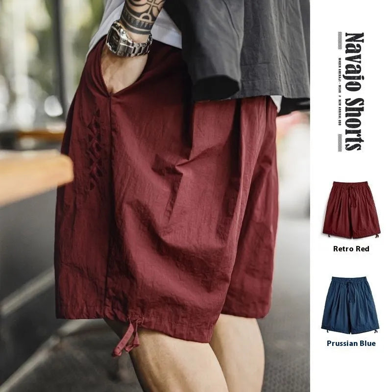 Men's Prussian Blue loose-fit nylon beach shorts with embroidered detail on a white background.