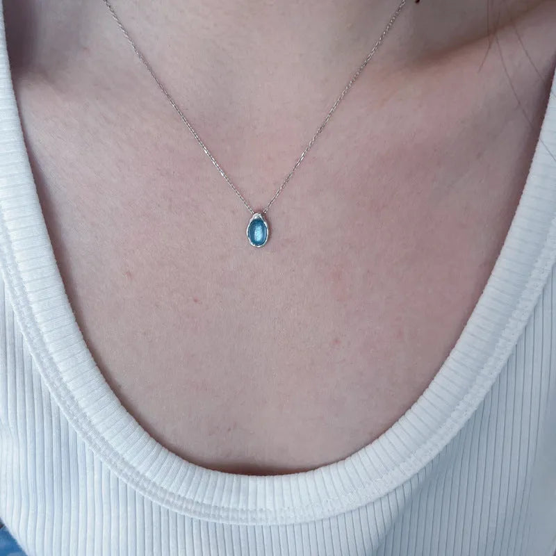 Navy blue and white gold geometric water drop pendant necklace on a cross chain for women.