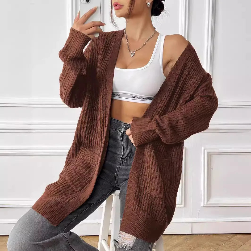 Women's dark green loose fit acrylic cardigan sweater with long sleeves on a hanger.