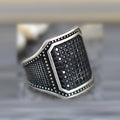 Close-up of a black alloy ring with a zircon stone and copper-coloured inlay detailing on the band.