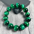 Green tiger eye gemstone bracelet with geometrically polished beads on a white background.