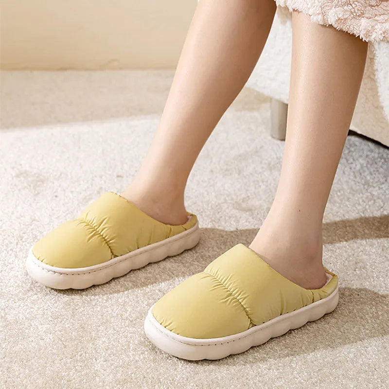 Blue down cotton slippers with artificial leather upper, thick rubber sole, and plush lining shown on a wooden floor.