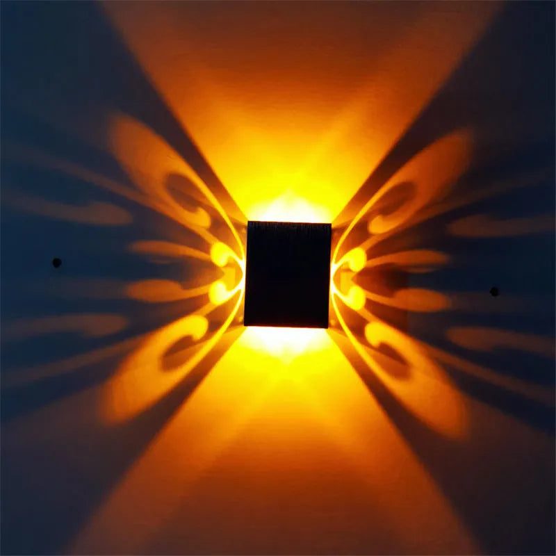 Modern aluminium butterfly-shaped LED wall lamp with remote control on a plain background.
