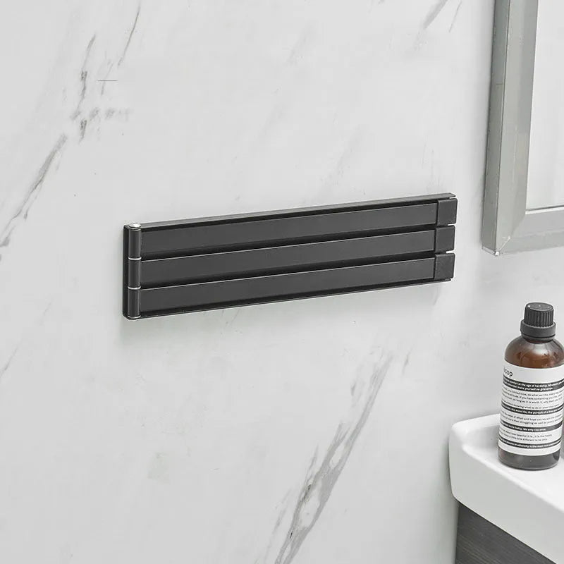 Black folding towel bar mounted on a bathroom wall with no visible screws or drill holes.