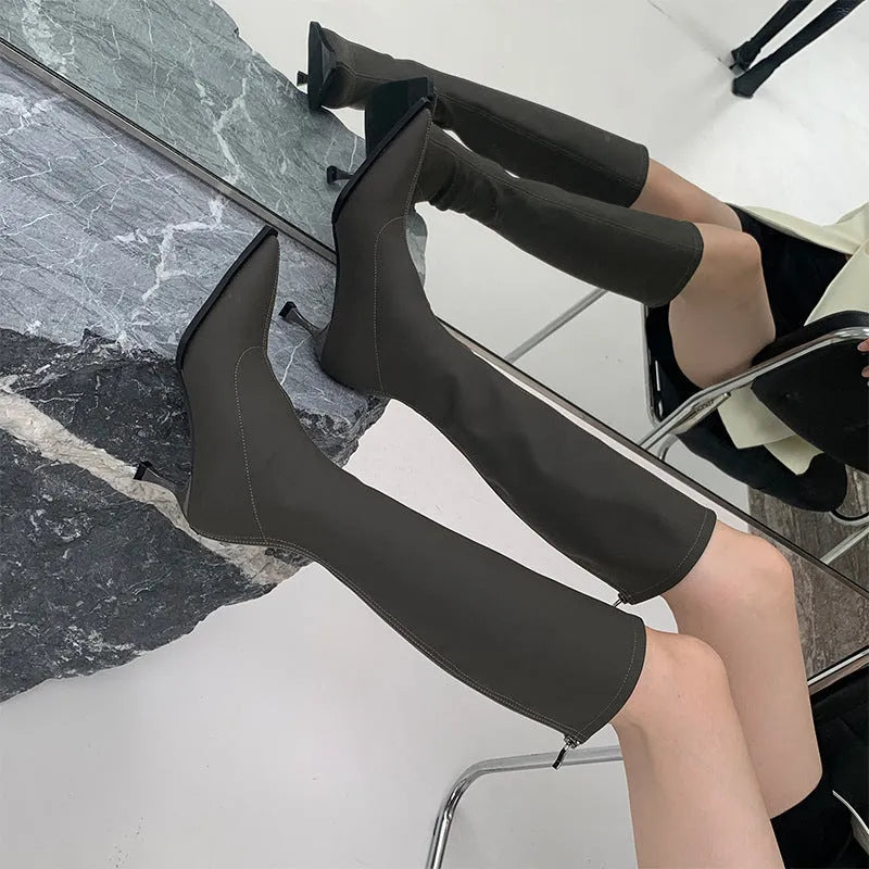 Women's black pointed-toe below-the-knee boots with a stiletto heel and a back zip fastening.