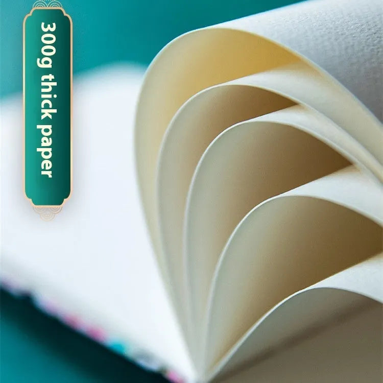 Feiluniao fabric-covered watercolour notebook open on a table with art supplies.