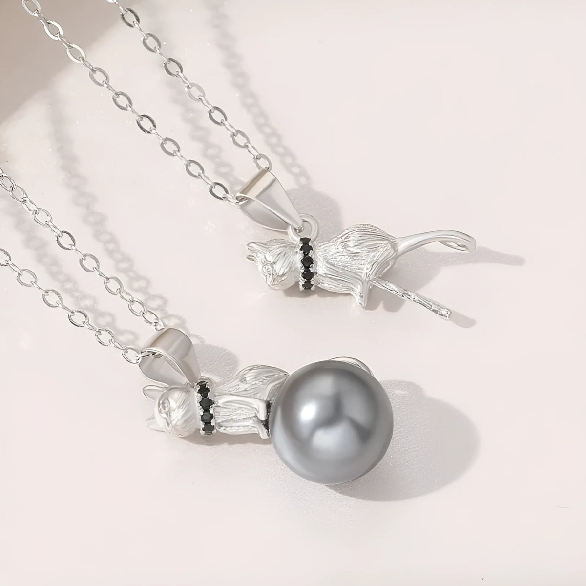Close-up of a sterling silver cat pendant necklace on a clavicle chain.