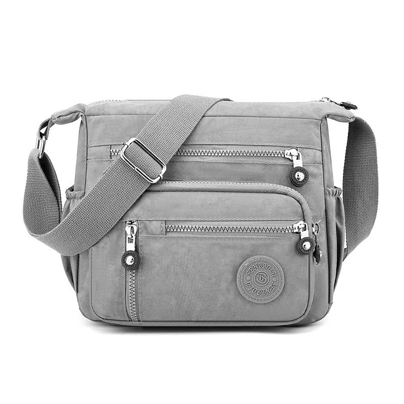Grey nylon messenger bag with single shoulder strap showing square vertical shape and lining interior