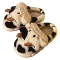 White plush cow slippers for women with black spots, a smiling face, and a textured non-slip sole.