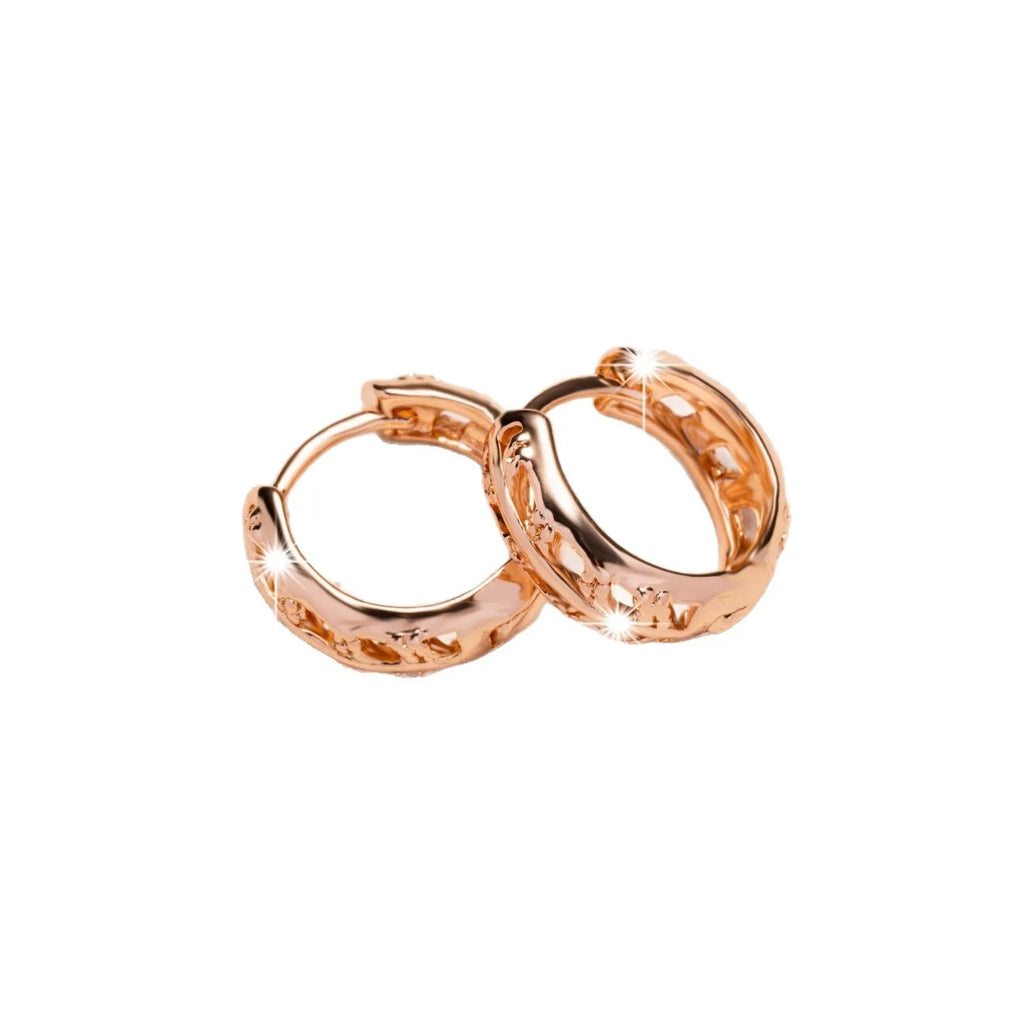 Rose gold hollowed out heart and leaf shaped copper earrings on a white background.