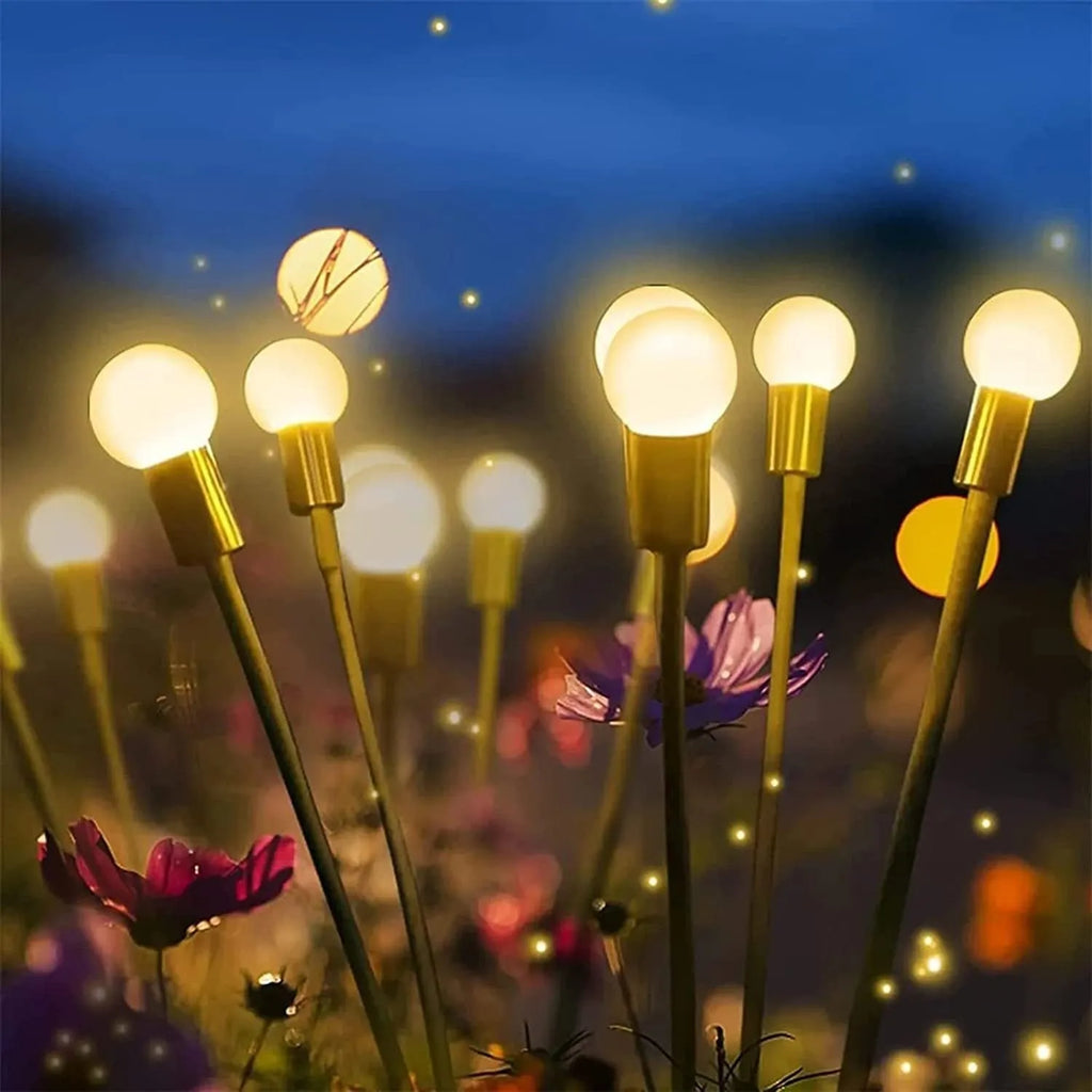 Solar-powered LED firefly ground spike light with multiple heads inserted along a garden path.