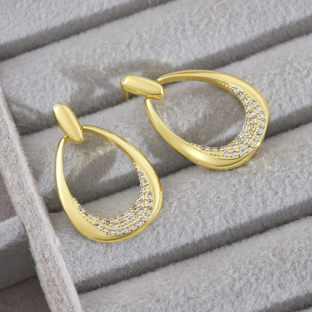 Yellow gold geometric drop earrings with round and oval ring elements on white background