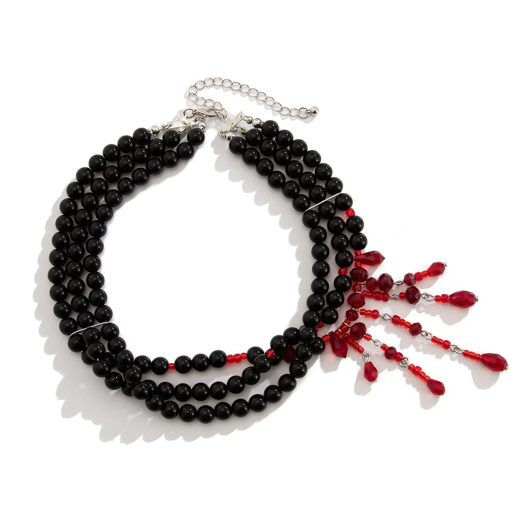 Men's Halloween necklace with red artificial crystal blood drop pendant and black imitation pearl tassels on a metal chain.