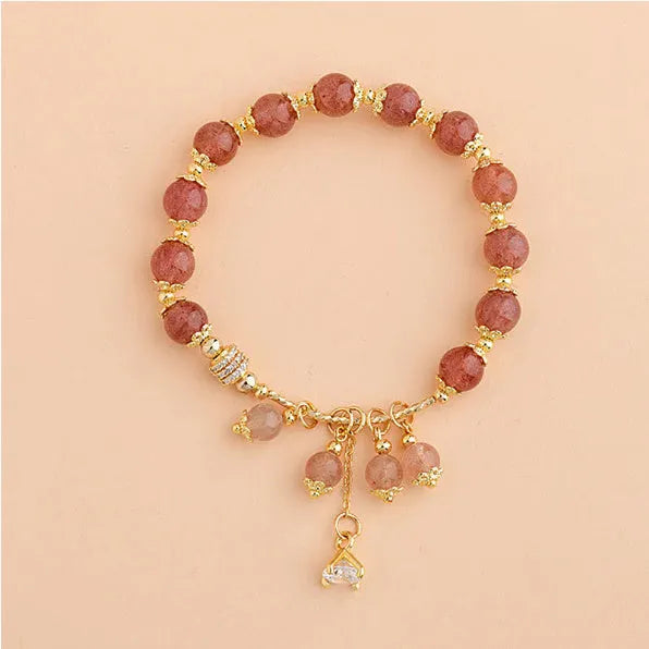 Close-up of a women's pink bracelet with a heart-shaped strawberry quartz crystal and small pearl accents on the band.
