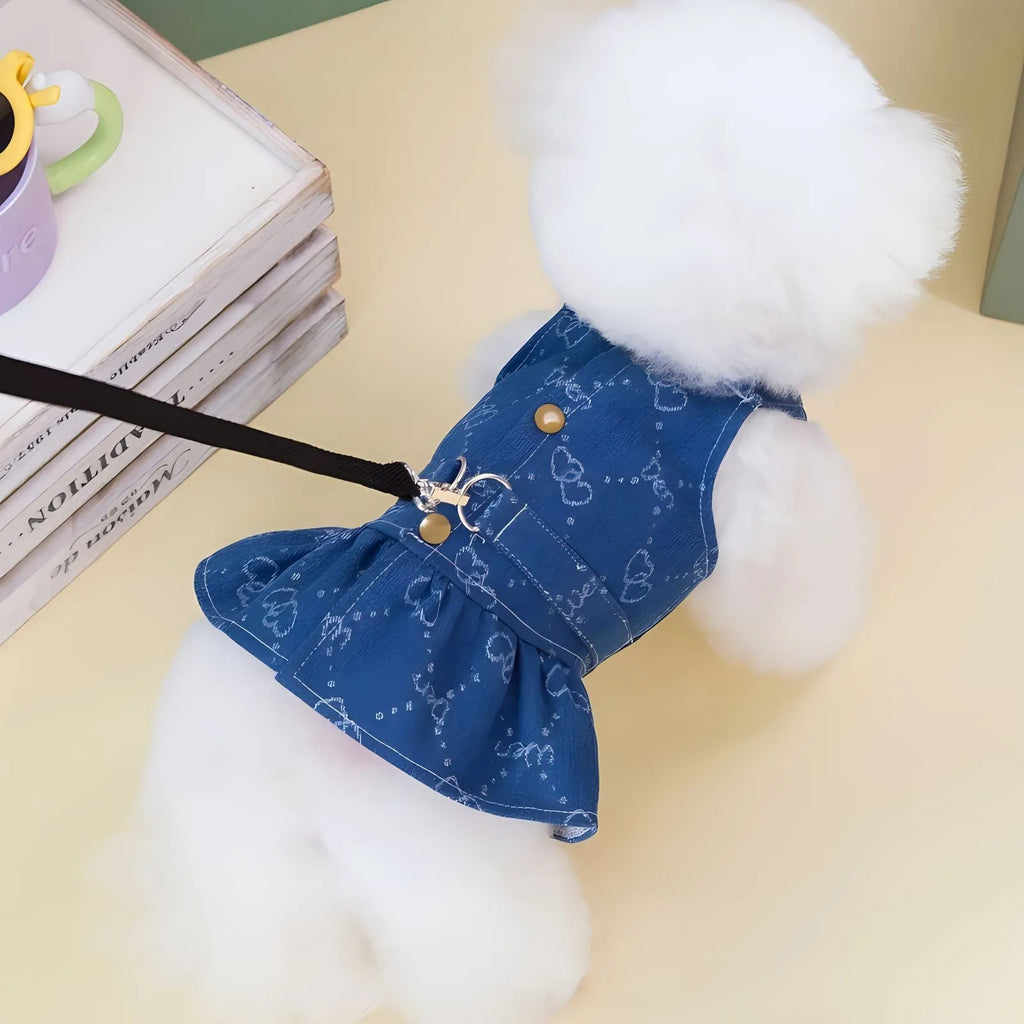 Small white dog wearing a light blue denim bracket-skirt princess dress.