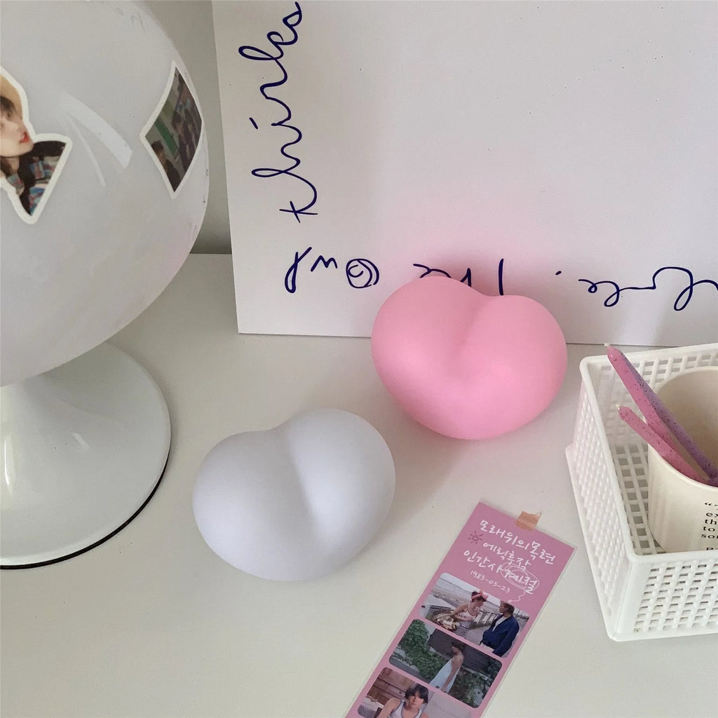 White and pink vinyl love-shaped atmosphere lamps in two sizes on a shelf.