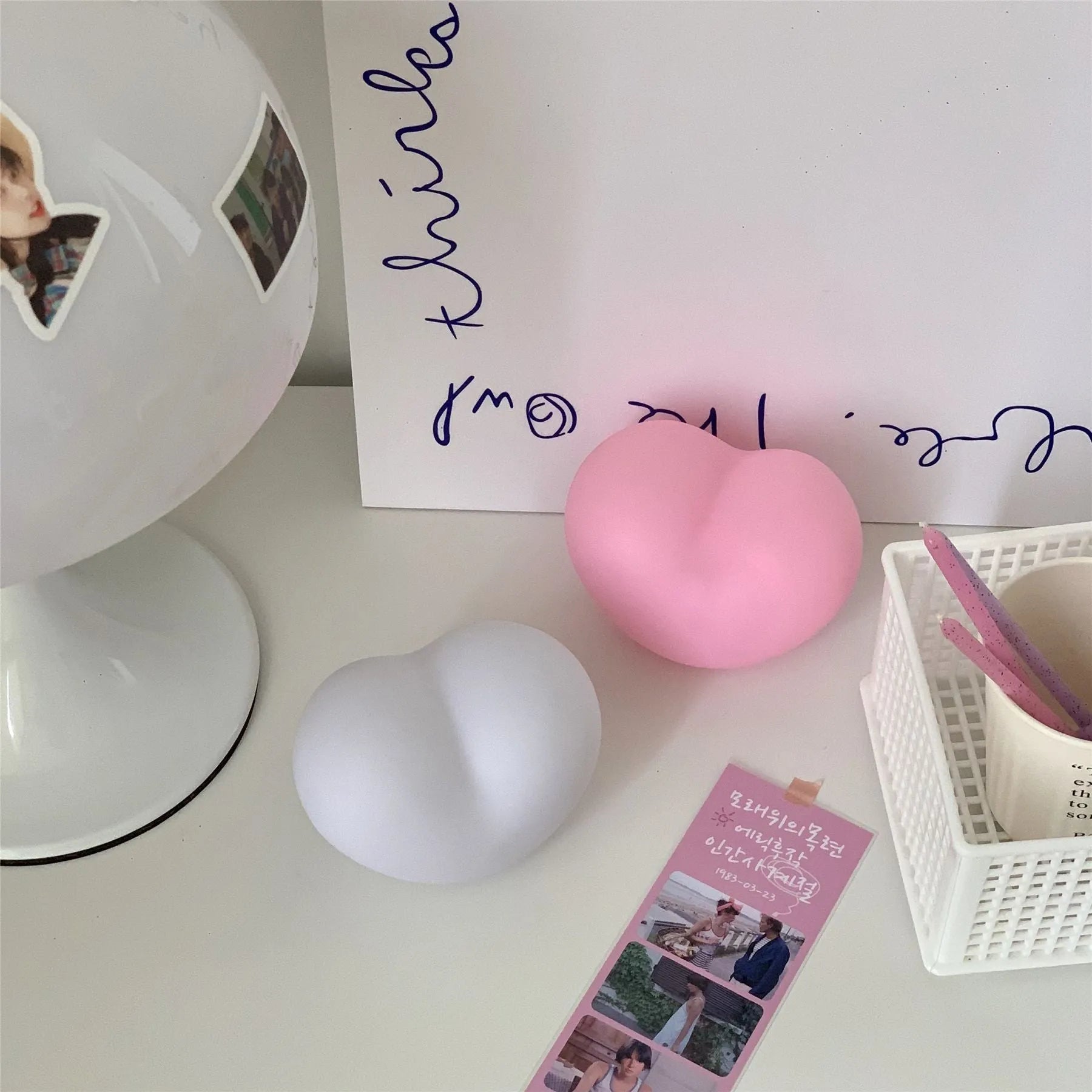 White and pink vinyl love-shaped atmosphere lamps in two sizes on a shelf.