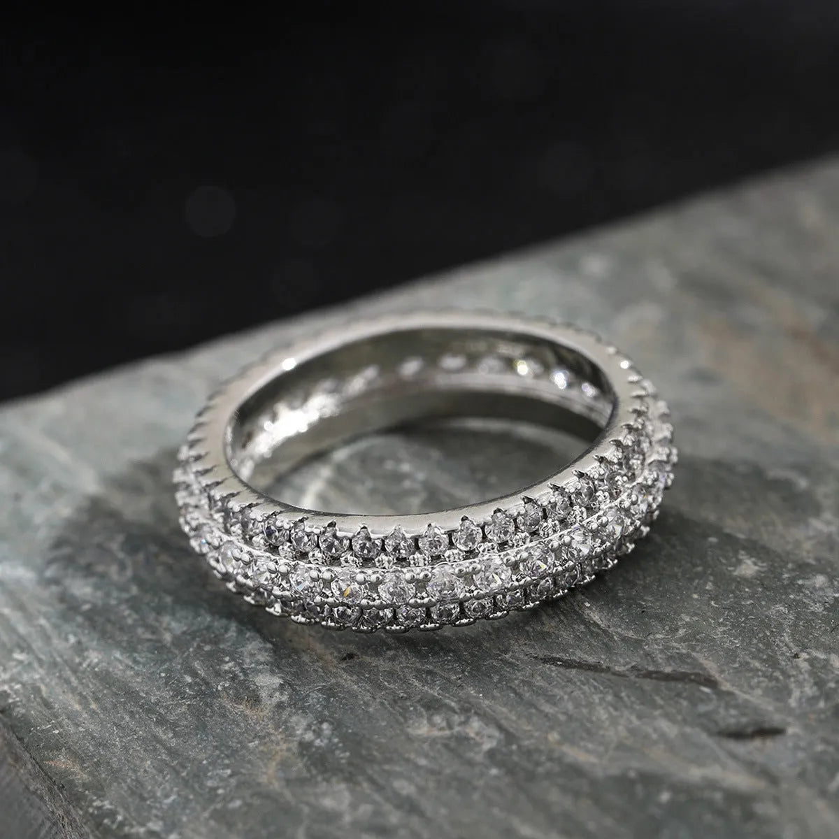 Geometric copper ring with a triangular zircon stone inlay, shown in white gold, yellow gold, and white and black plated finishes.