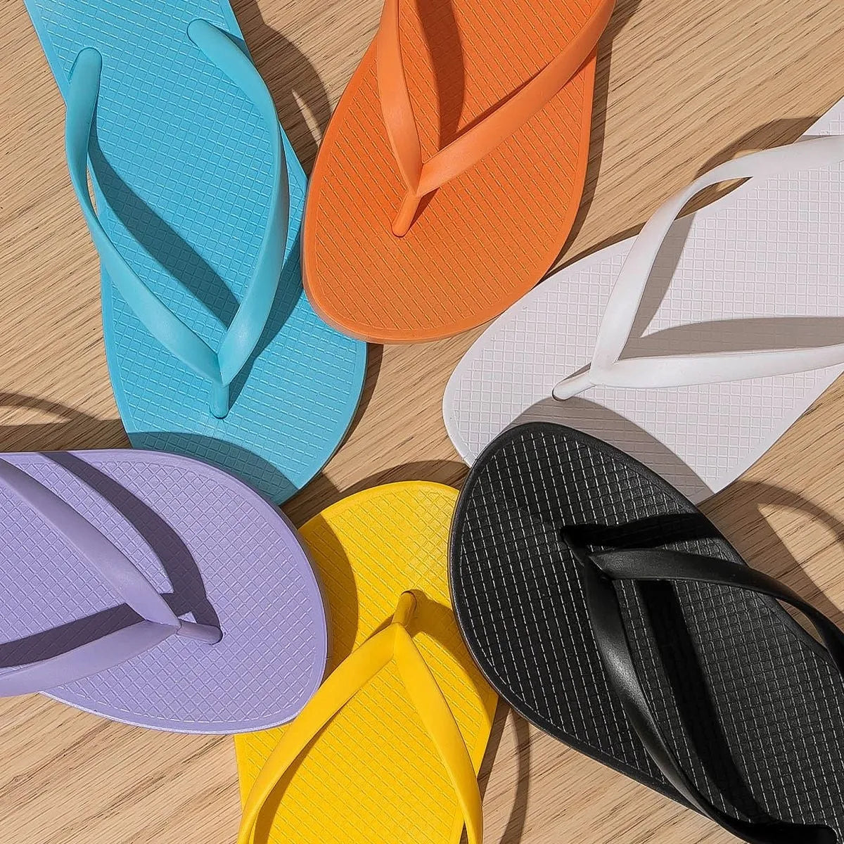 Foldable flat slippers with a non-slip PVC sole and hollow-out design in orange, purple, black, and white.