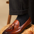 Men's black leather tassel loafers with rubber sole shown from side view
