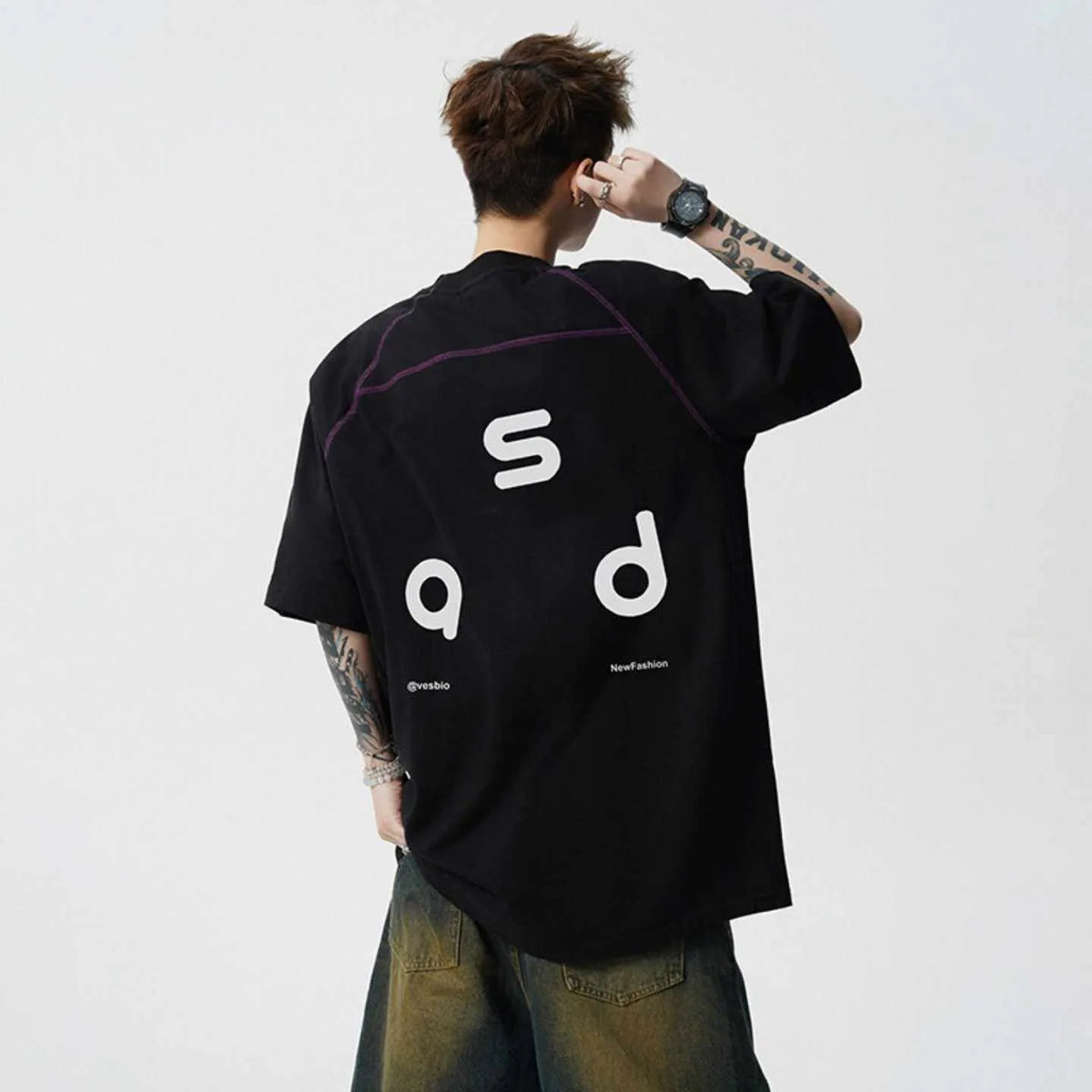 Loose-fitting black cotton T-shirt with a letter print on the chest, showing short sleeves and a round neck.