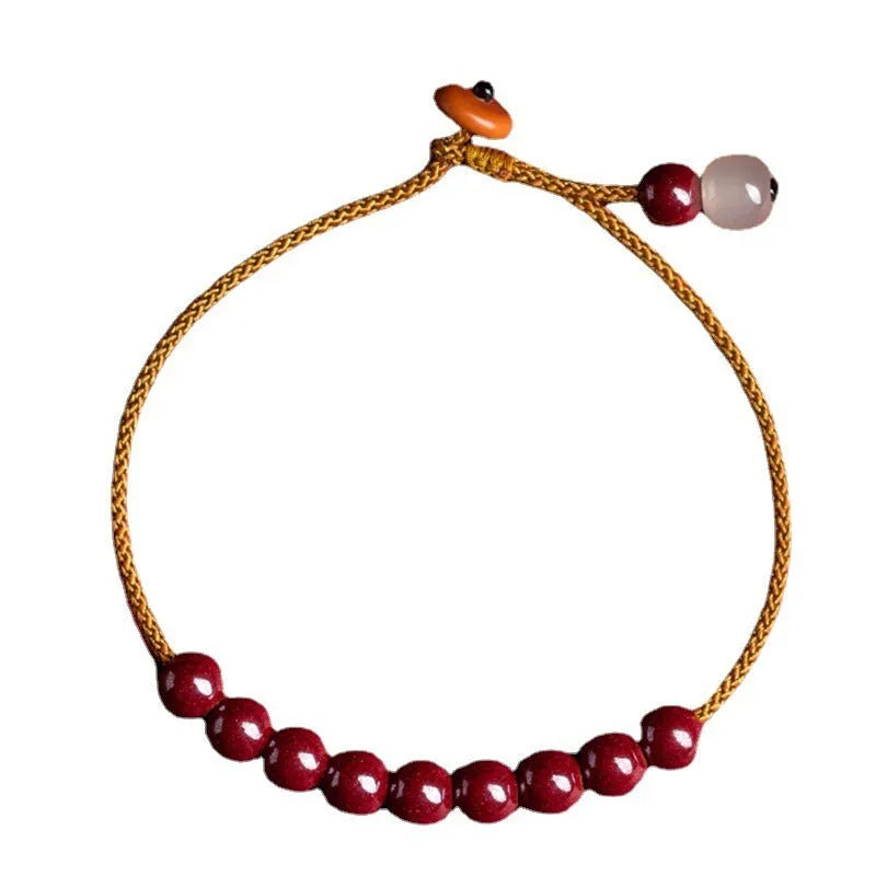 Close-up of a geometric design bracelet made from dark red cinnabar and Hetian jade on a wrist.