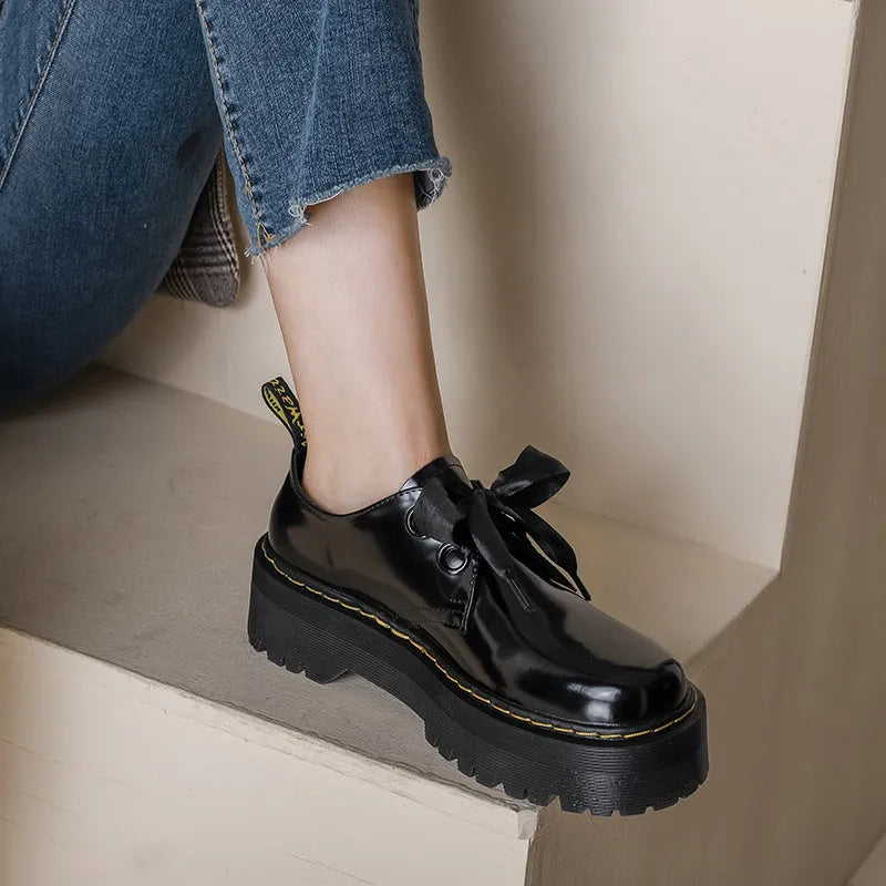 Women's black thick-soled leather shoes with cross-strap closure and ribbon detailing