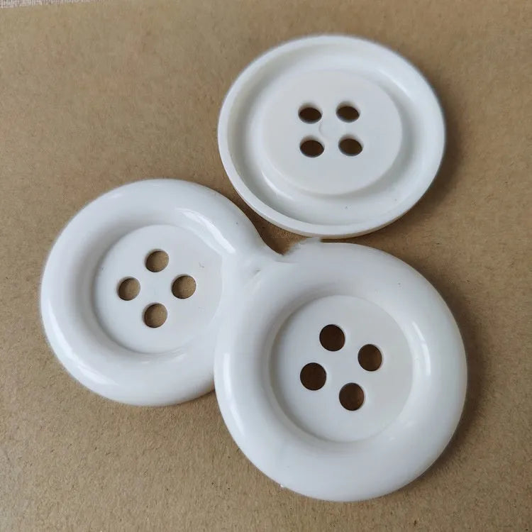 Assortment of oversized round plastic buttons in multiple colours showing four-hole design.