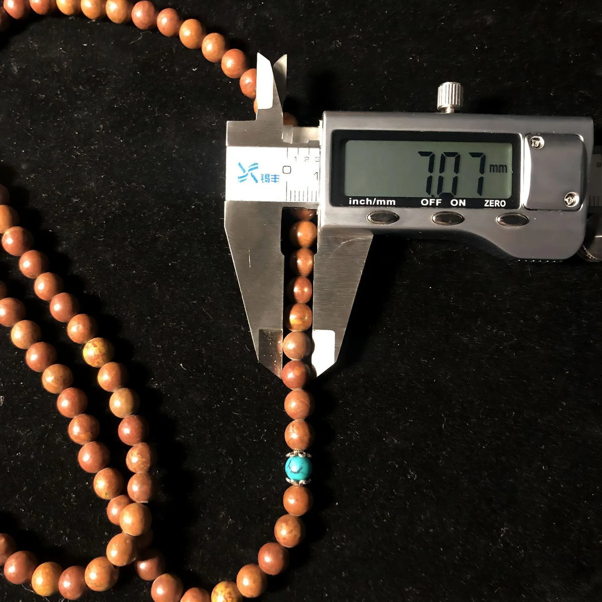 Handmade stone bead bracelet with 108 round geometric beads on a wrist.