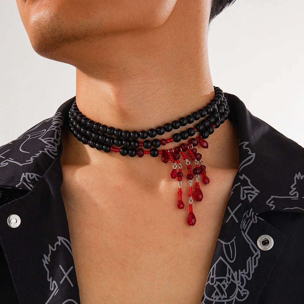 Men's Halloween necklace with red artificial crystal blood drop pendant and black imitation pearl tassels on a metal chain.