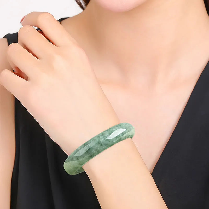 Natural emerald green stone bracelet for women on a wrist, presented with its certificate and gift box.