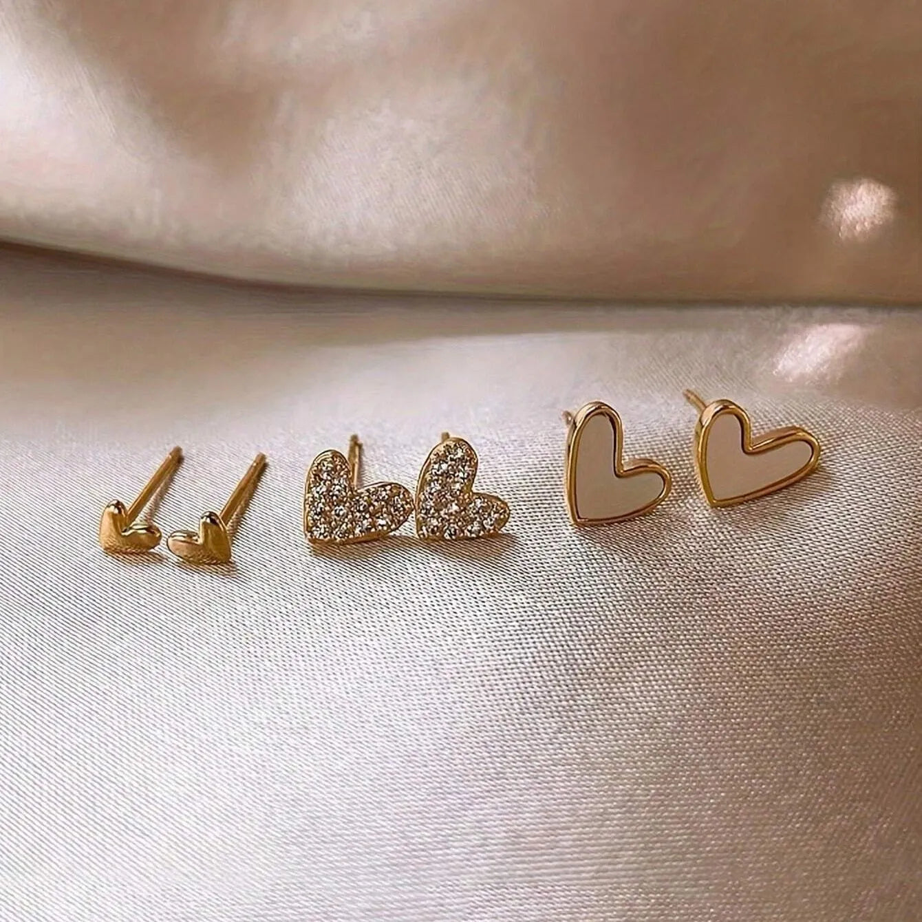 Three pairs of women's heart-shaped alloy earrings in gold, black, pink and black-white colours