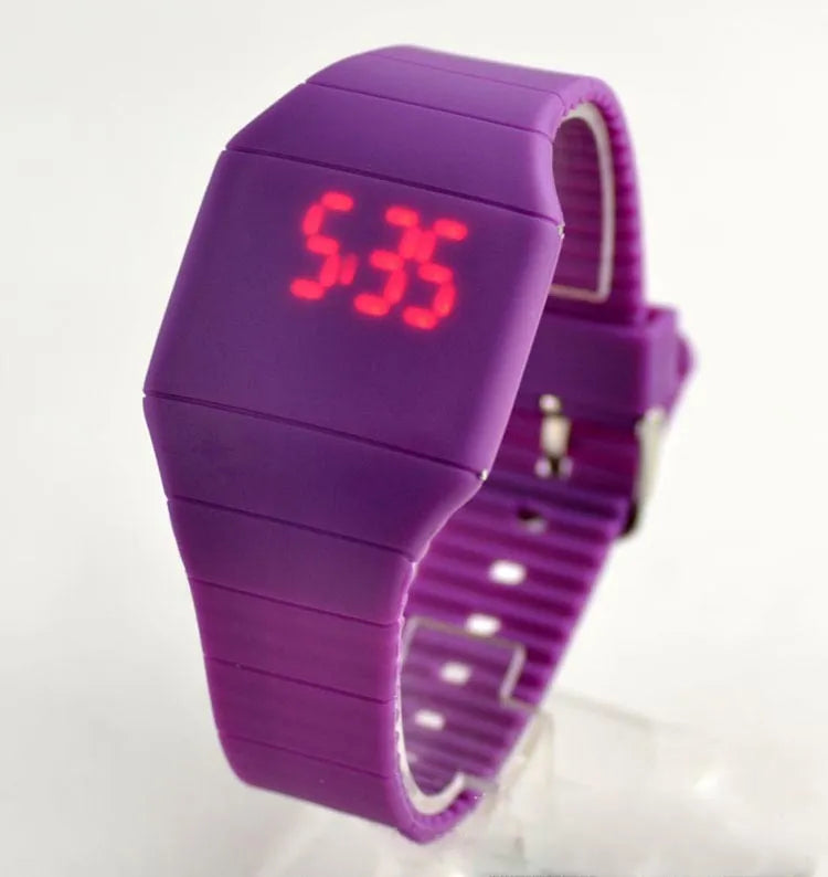 Square white electronic watch with digital display on wrist, showing touch screen and stainless steel buckle