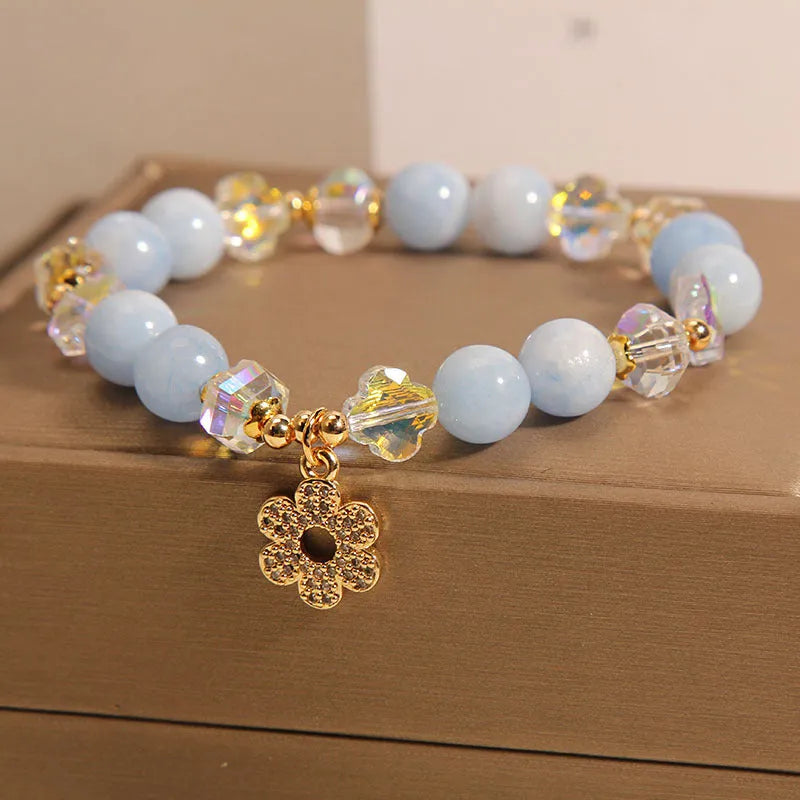 Aquamarine crystal bracelet with a four-leaf clover charm and a pearl decorative element on a wrist.