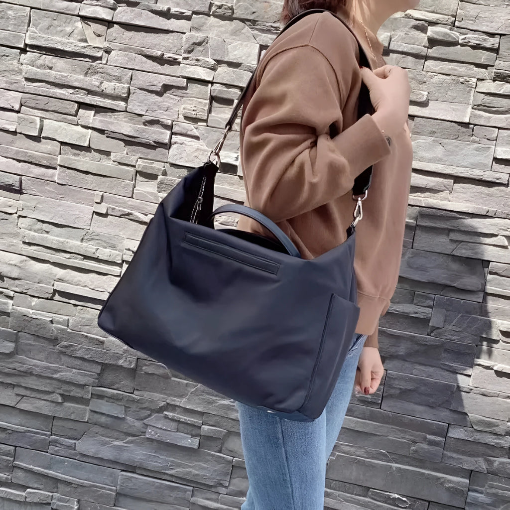 Waterproof nylon shoulder bag with leather trims in black or light khaki colour, showing 35cm dimensions