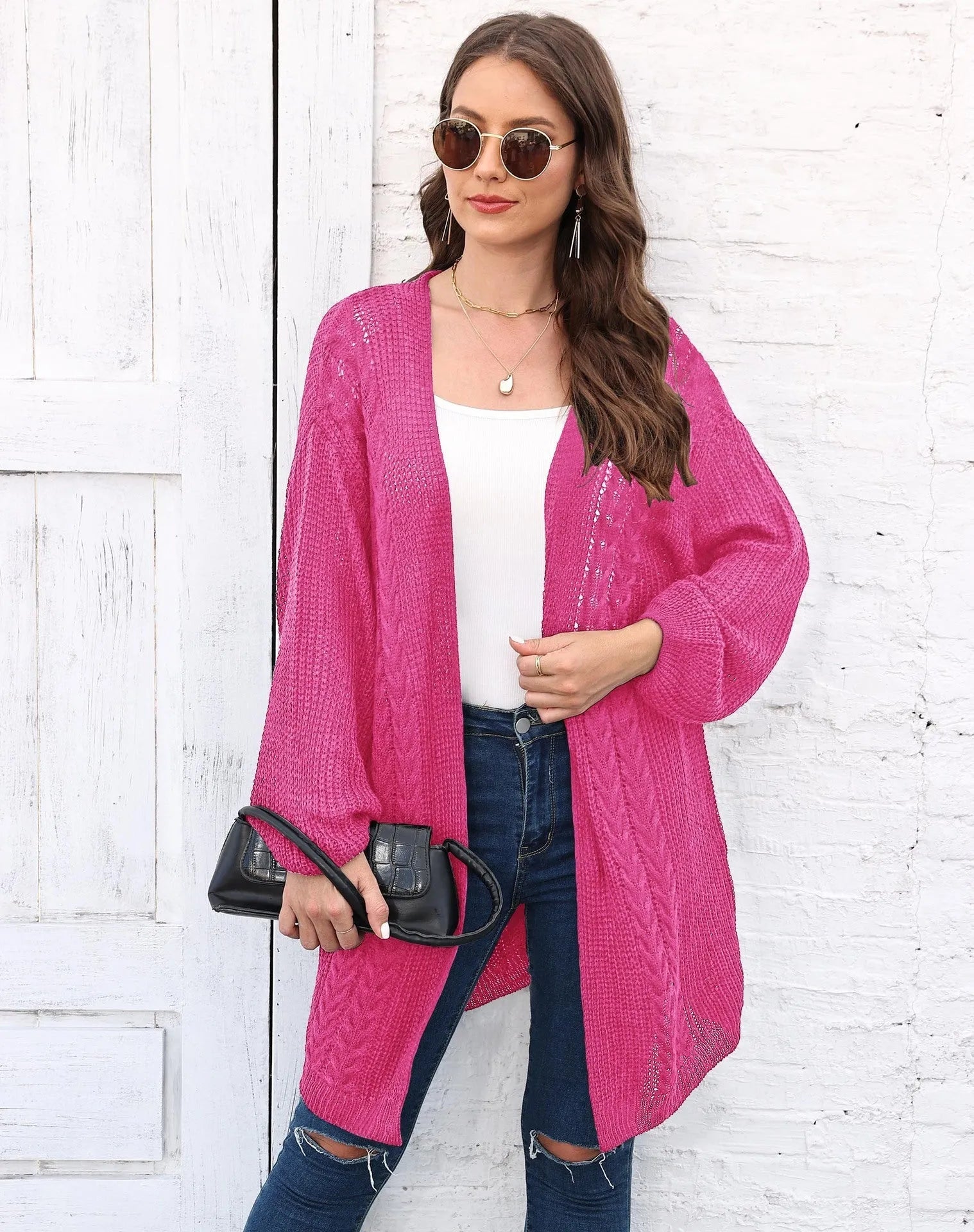 Women's loose-fitting long sleeve acrylic sweater coat in a solid colour on a hanger.