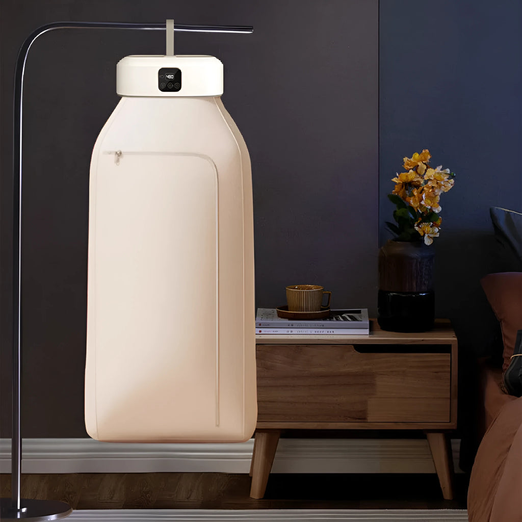 White cylindrical foldable clothes dryer with remote control on a table.