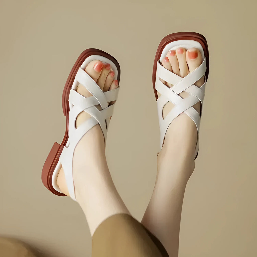 Women's black patent leather beach sandals with square toe and cross-strap design on a light background.