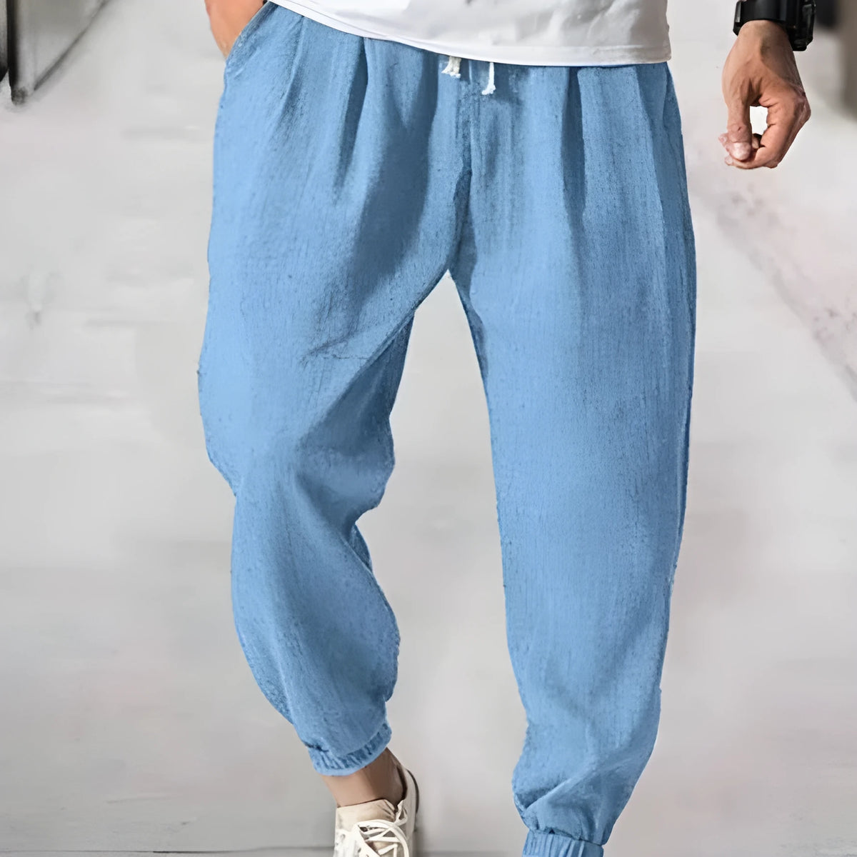 Man modelling loose fit cotton trousers with elasticated ankle cuffs in a light green colour.